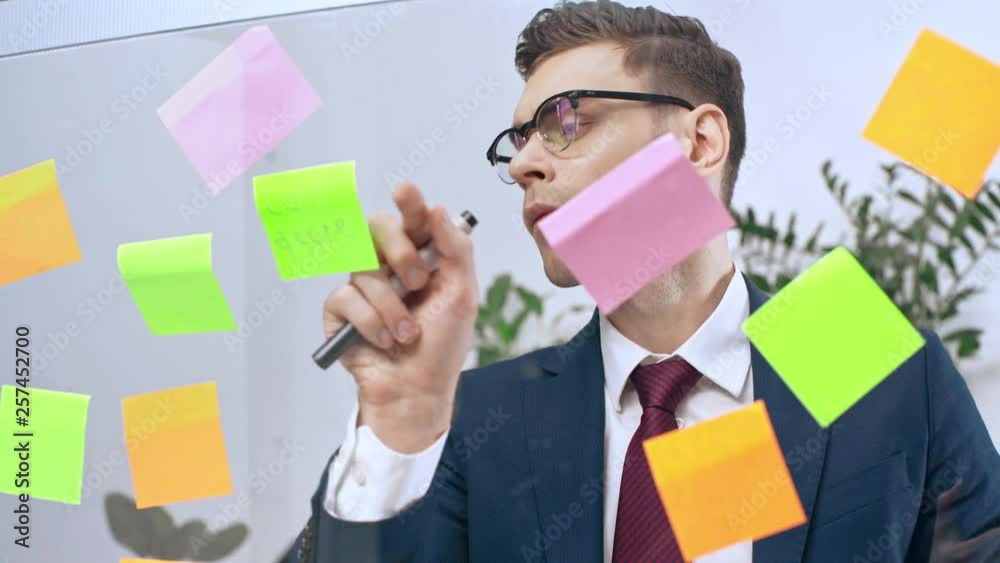 handsome, attentive businessman writing on sticky notes