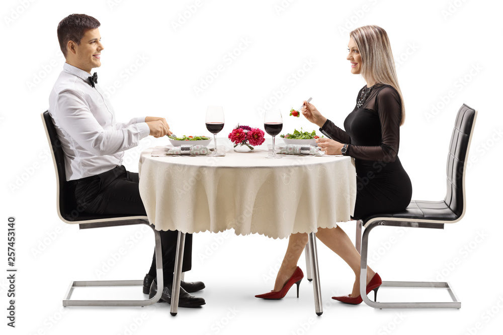 Young man and woman eating salad at a table Young man and woman eating salad at a table