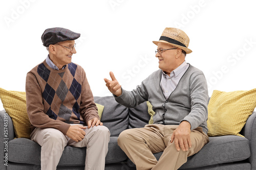 Two elderly men sitting on a sofa and talking