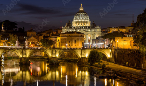 Rome at Night - A panoramic night view of Tiber river at Sant' Angelo Bridge, with St. Peter's Basilica towering in background, as seen from the Ponte Umberto bridge. Rome, Italy.