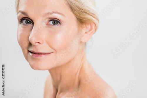 attractive and blonde mature woman looking at camera isolated on grey