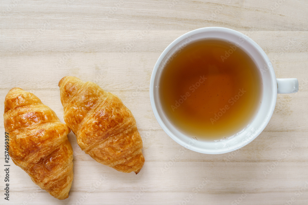 Croissant and a cup of tea on a wooden tray Croissant and a cup of tea on a wooden tray