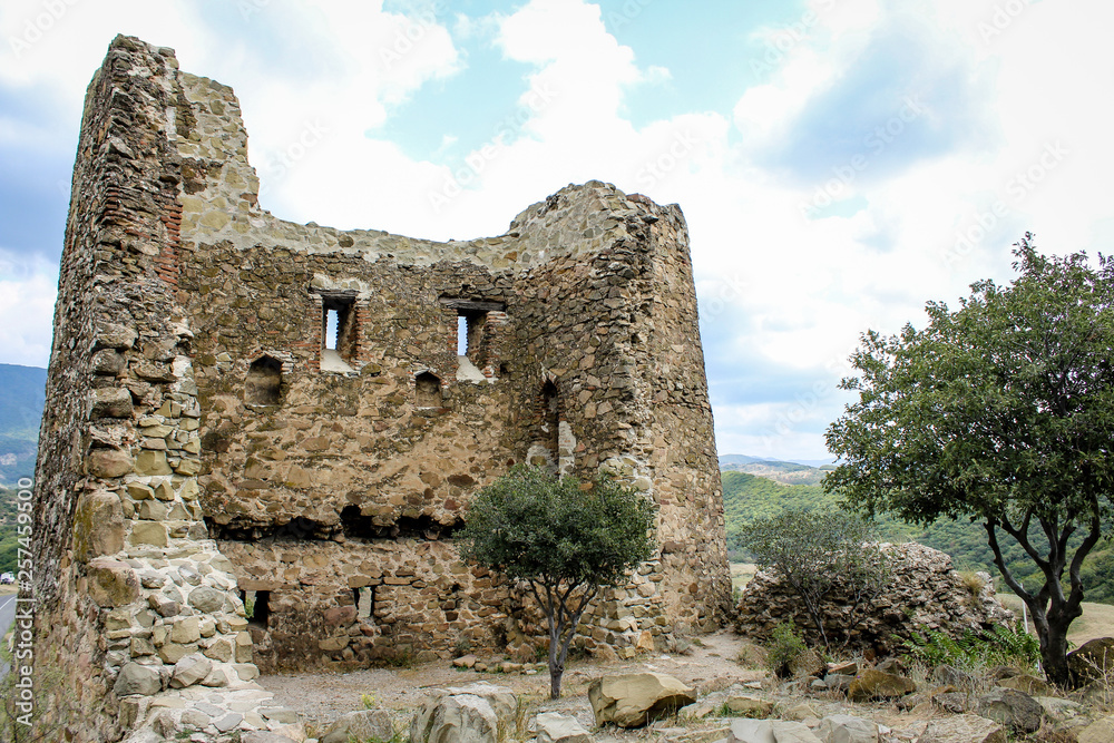 Destroyed building with windows, Jvari Monastery, Georgia. Ancient stone ruins and young green trees. Drought, church, fortress, Europe, wall. old architecture. The history of the country. Summer