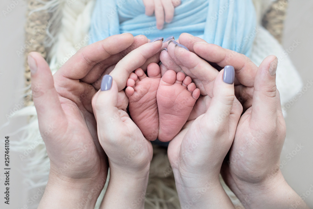 Feet of a newborn baby, toes in the hands of mom and dad, hands and nails of a child, the first days of life after birth, scaly skin