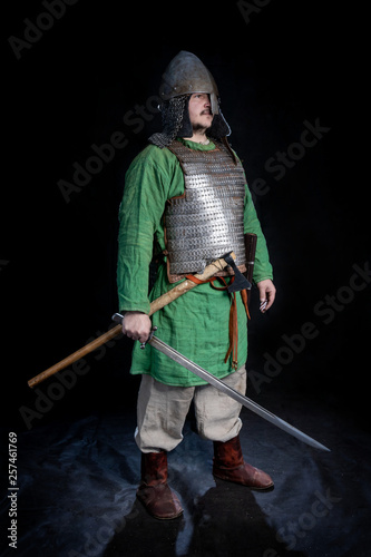 Photography slavic viking age warrior in armor and helmet  with sword and ax