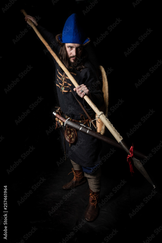 a man in clothes and with weapons of the Viking Age threatens with a spear a man in clothes and with weapons of the Viking Age threatens with a spear