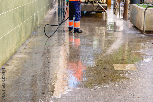 Cleaning worker throwing pressure water to clean the sidewalks of a city.