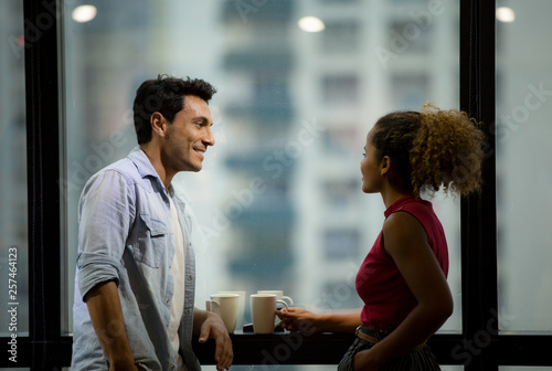 Foto Pleased male and female people with cups in arms relaxing by the casement