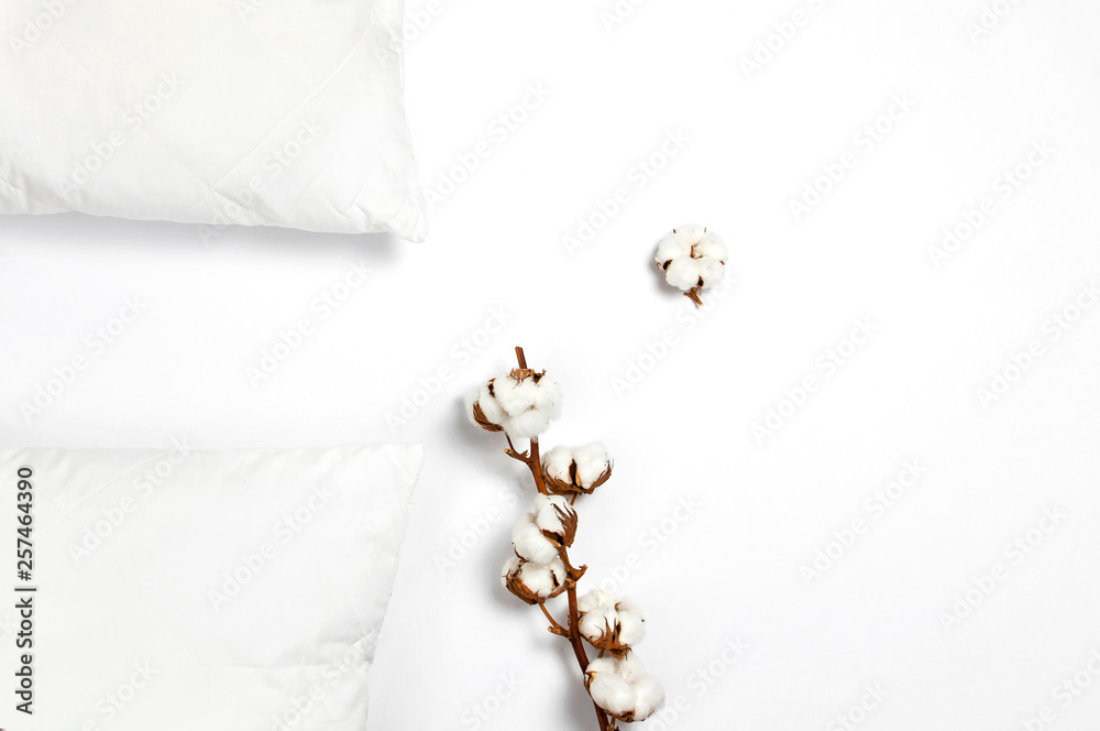 Soft white quilted pillow and branch of cotton on light background top view. Clean pillow, interior item, bedding mockup design template - obrazy, fototapety, plakaty 