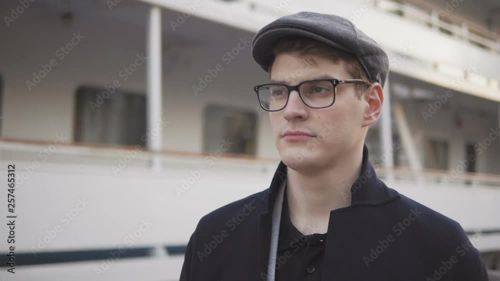A young man standing near the ship looking dval with a serious face. A young man standing near the ship looking dval with a serious face.