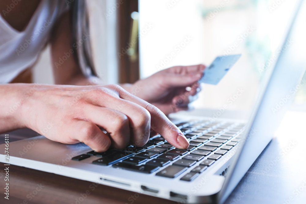 Frau hält Kreditkarte und kauft Online am Laptop ein Frau hält Kreditkarte und kauft Online am Laptop ein