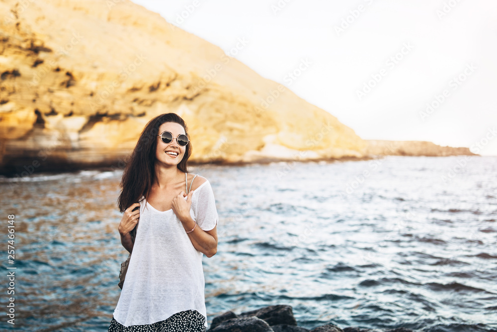 Pretty long hair tourist girl relaxing on the stones near sea. Pretty long hair tourist girl relaxing on the stones near sea.