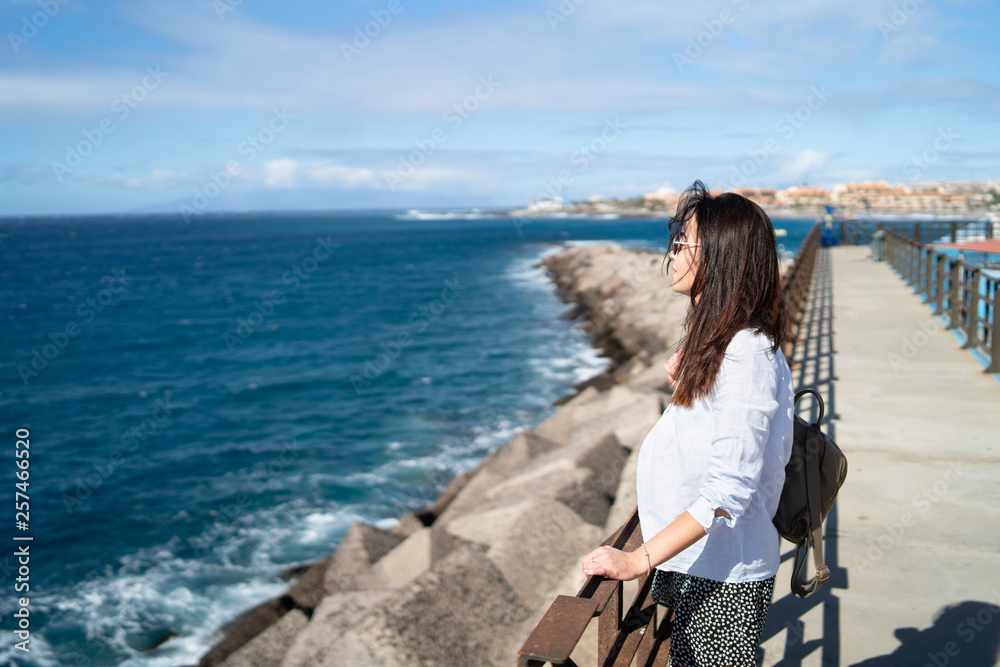 Pretty long hair brunette girl relaxing near ocean.
