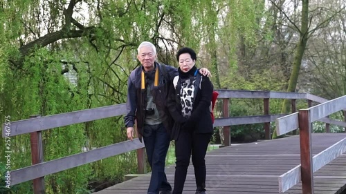 Asian senior couple travel to Europe walking in morning park