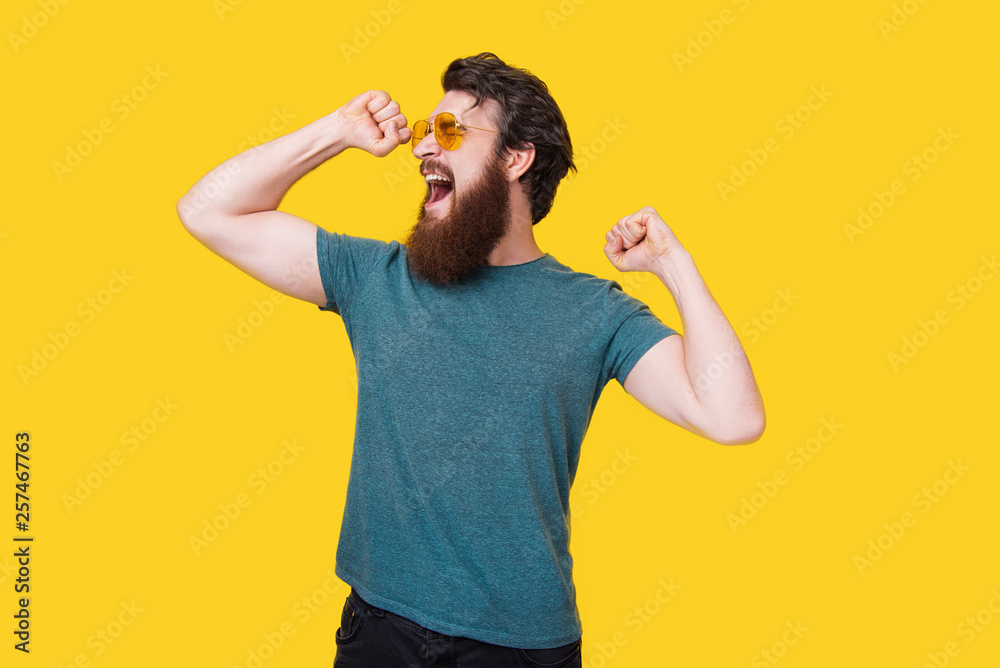 Handsome bearded man making a winner gesture on yellow background. Man yelling or yawning. Handsome bearded man making a winner gesture on yellow background. Man yelling or yawning.