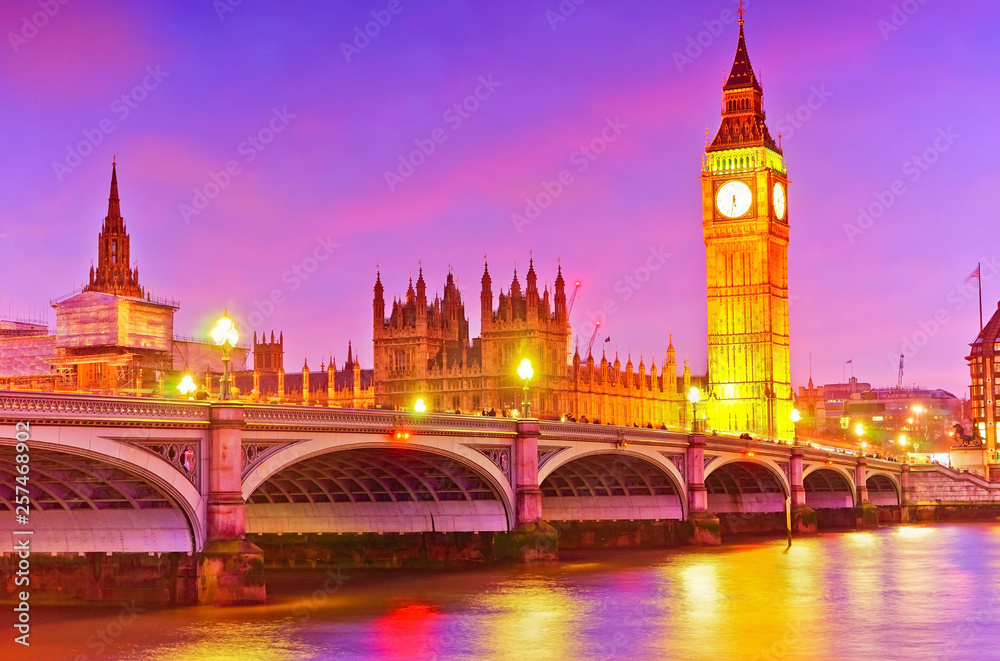 Naklejka premium View of the Houses of Parliament and Westminster Bridge along River Thames in London at night.
