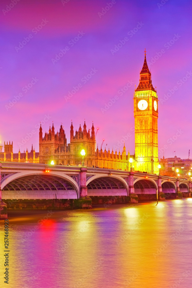 View of the Houses of Parliament and Westminster Bridge along River Thames in London at dusk.
