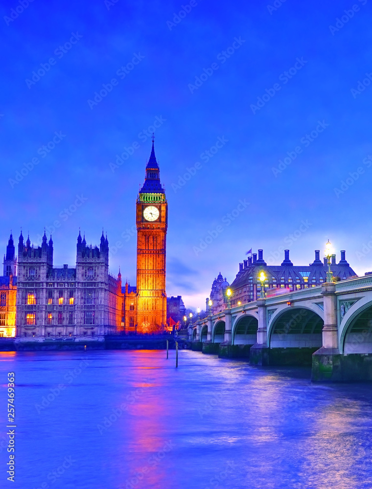 View of the Houses of Parliament and Westminster Bridge along River Thames in London at night.