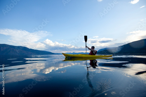 Young man paddles yellow kayak on Lake Pend Oreille in Sandpoint, Idaho.