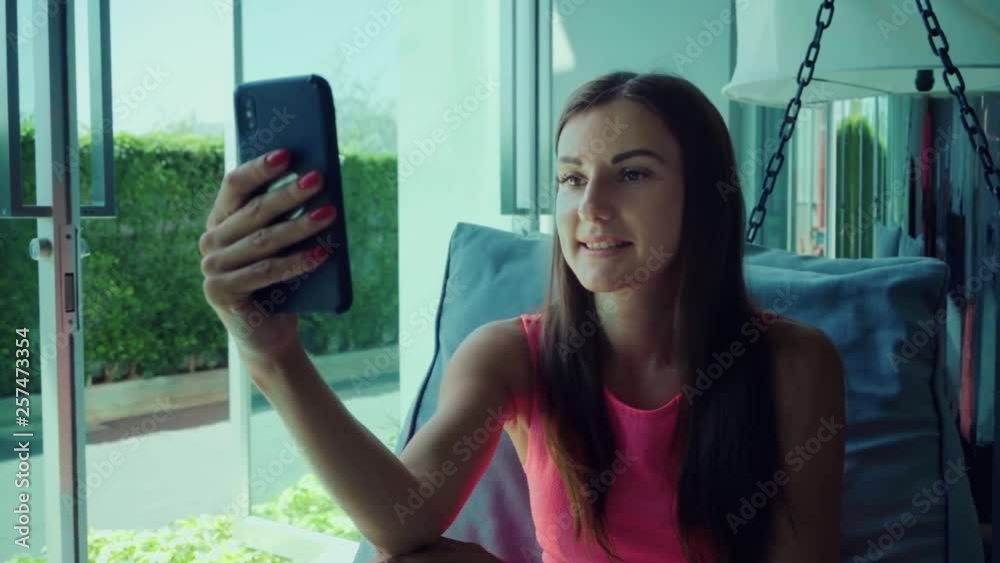 young girl talking on Skype on the phone while lying on a hanging bed in the afternoon, slow motion. close-up