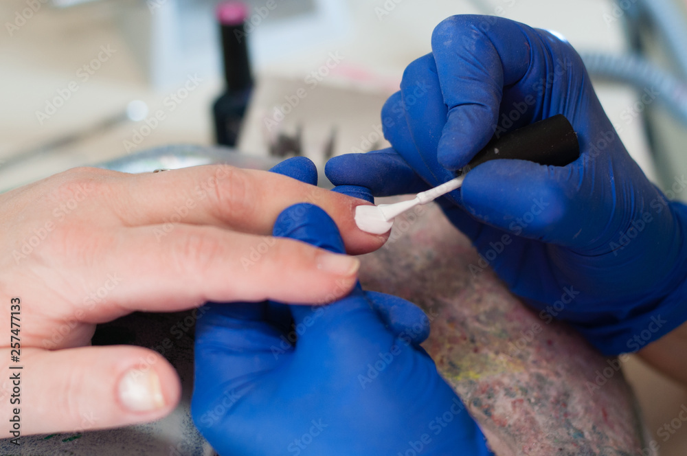 Manicure process of white nail polish in a spa salon. Concept beauty services. Beautiful female hands closeup Manicure process of white nail polish in a spa salon. Concept beauty services. Beautiful female hands closeup