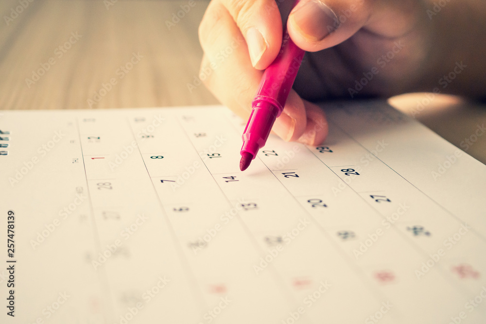 Hand with pen writing on calendar page closeup Hand with pen writing on calendar page closeup