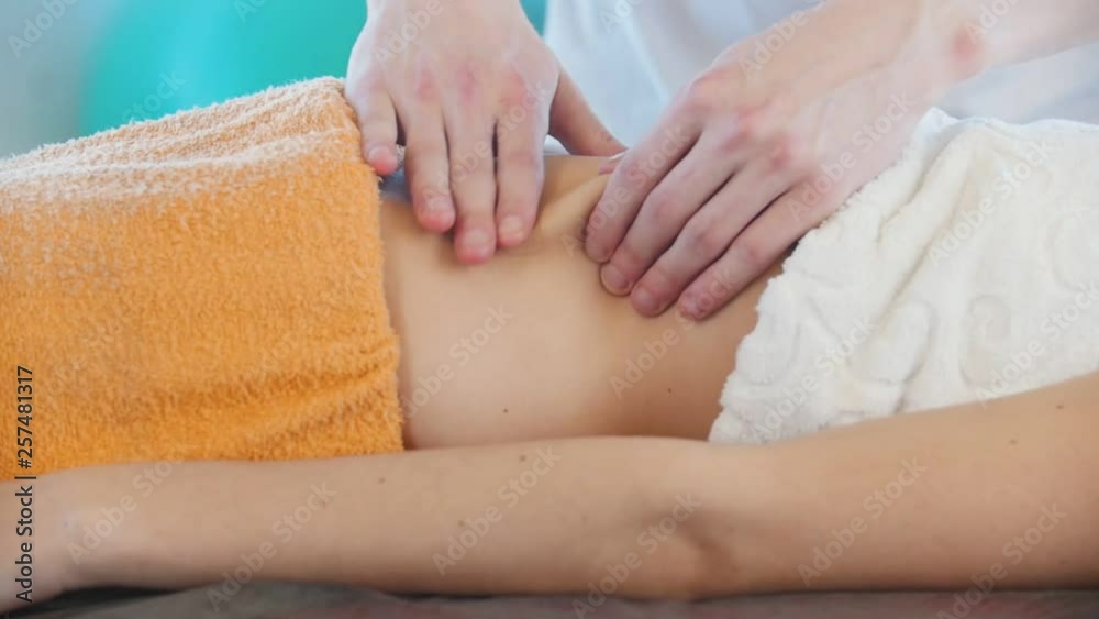 Massage session. A young woman receiving a massage. Massaging the stomach. Side view Massage session. A young woman receiving a massage. Massaging the stomach. Side view