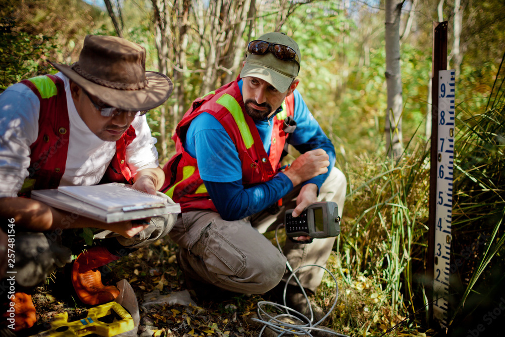 Two scientist collect data at a stream gauge in the field. Two scientist collect data at a stream gauge in the field.