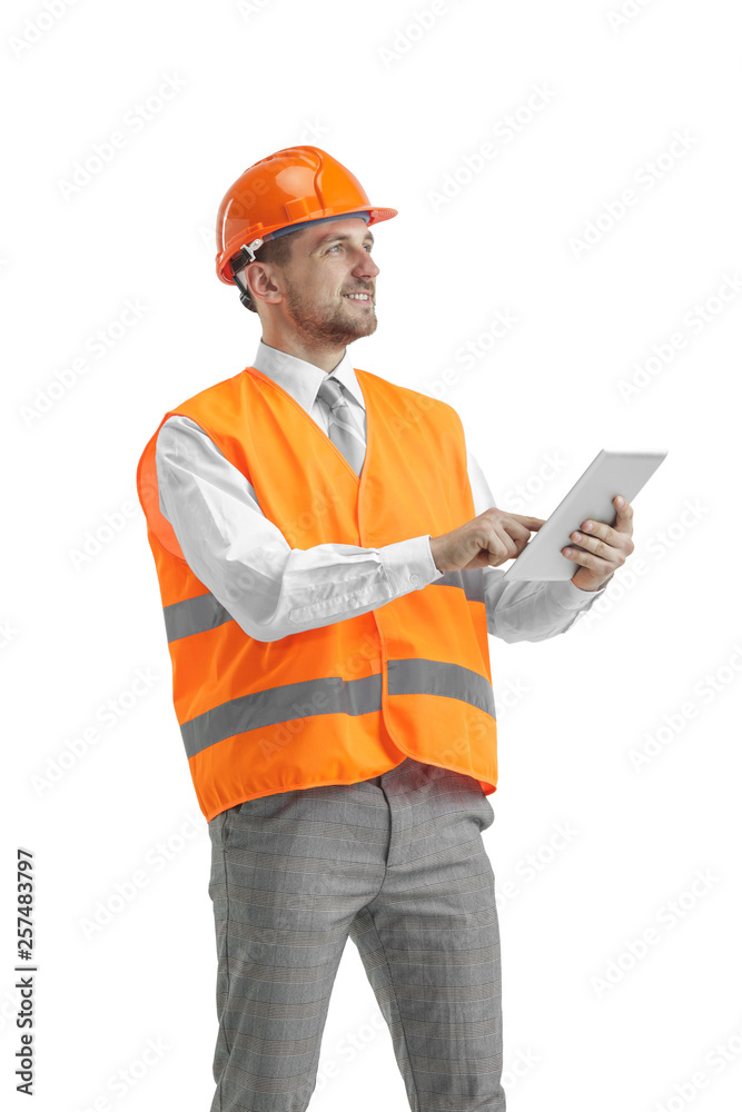 The builder in a construction vest and an orange helmet with tablet. Safety specialist, engineer, industry, architecture, manager, occupation, businessman, job concept The builder in a construction vest and an orange helmet with tablet. Safety specialist, engineer, industry, architecture, manager, occupation, businessman, job concept