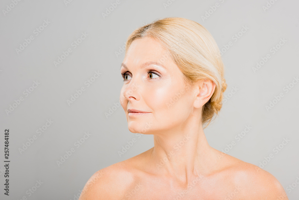 attractive and blonde mature woman looking away on grey background attractive and blonde mature woman looking away on grey background