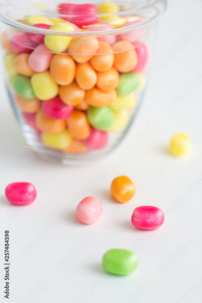 food, confectionery and sweets concept - close up of glass jar with colorful candy drops over white background food, confectionery and sweets concept - close up of glass jar with colorful candy drops over white background