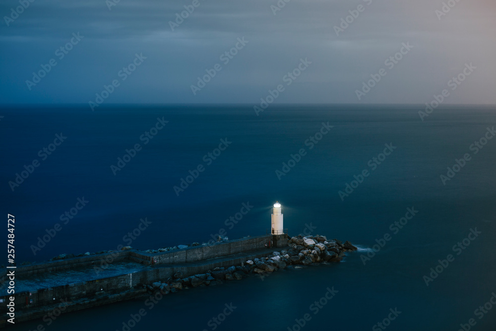 Tranquil seascape with lone lighthouse and pier at dusk, Camogli, Liguria, Italy Tranquil seascape with lone lighthouse and pier at dusk, Camogli, Liguria, Italy