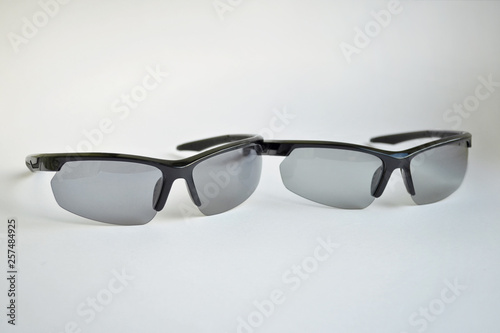 Two sport black sunglasses with photochromic and polarizing effect on white background