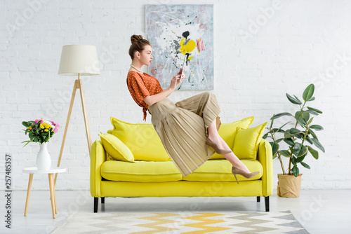 elegant young woman levitating in air and using digital tablet in living room photo