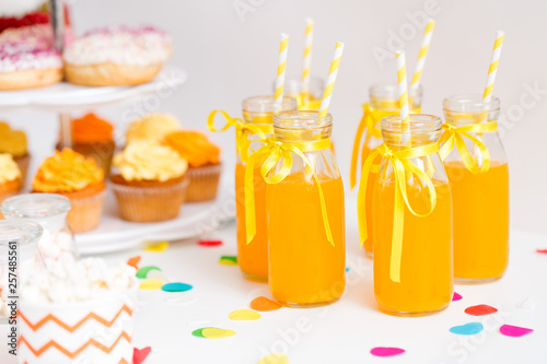 Photography birthday party and drinks concept - orange juice in glass bottles with paper str