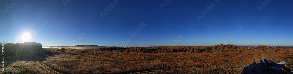 Amazing panorama of the rural autumn landscape of a European village with a colorful sky and an infinite golden field.
