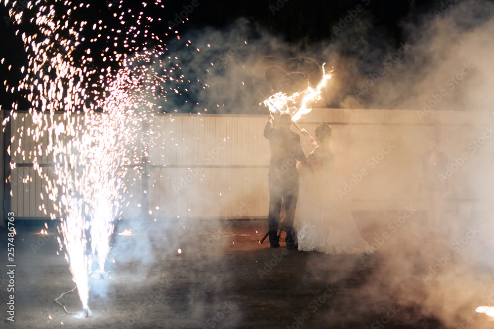 beautiful young newlywed couple with fire torches in their hands and fireworks 1
