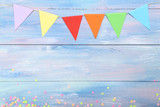 Colorful confetti and paper flags on blue wooden background