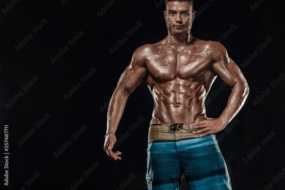 Fototapeta premium Bodybuilding competitions on the scene. Man sportsmen physique and athlete. Black background with lights.