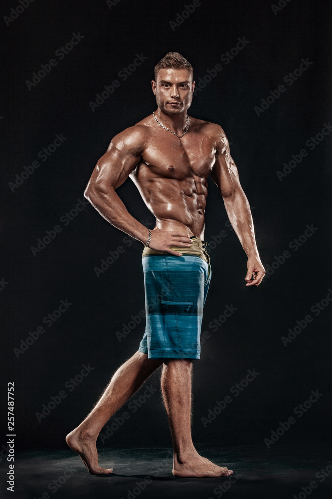 Fototapeta premium Bodybuilding competitions on the scene. Man sportsmen physique and athlete. Black background with lights.