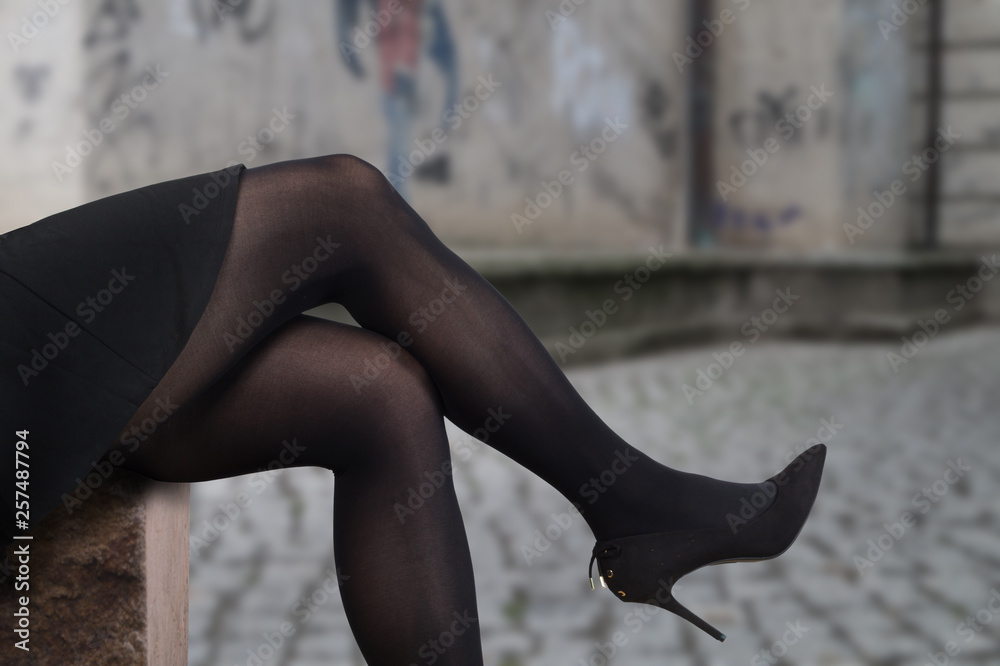 Sexy female legs wearing high heels and black tights. Sitting on a stone in  the city. Stock Photo | Adobe Stock