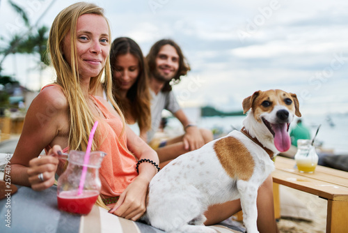 group of three russian tourists drinking cocktails at beach resort on koh samui thailand with pet dog