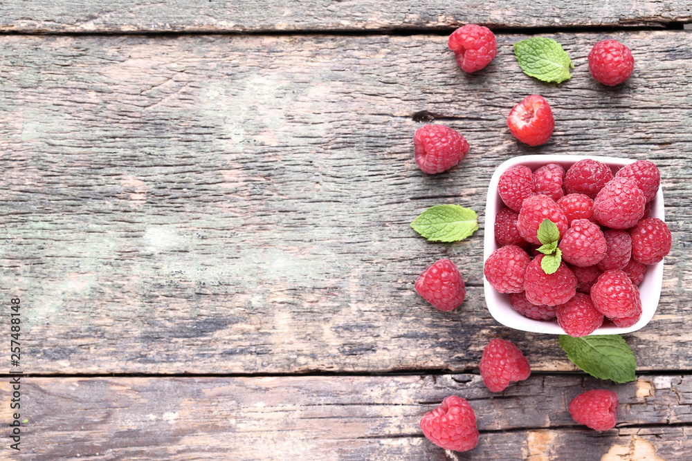 Ripe raspberries with green leafs on grey wooden table Ripe raspberries with green leafs on grey wooden table