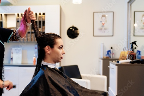 Woman hairdresser styling young woman customer hair in salon