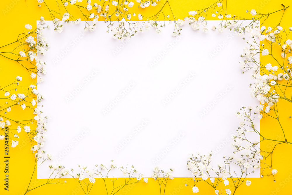 White gypsophila flowers with blank sheet of paper on yellow background White gypsophila flowers with blank sheet of paper on yellow background