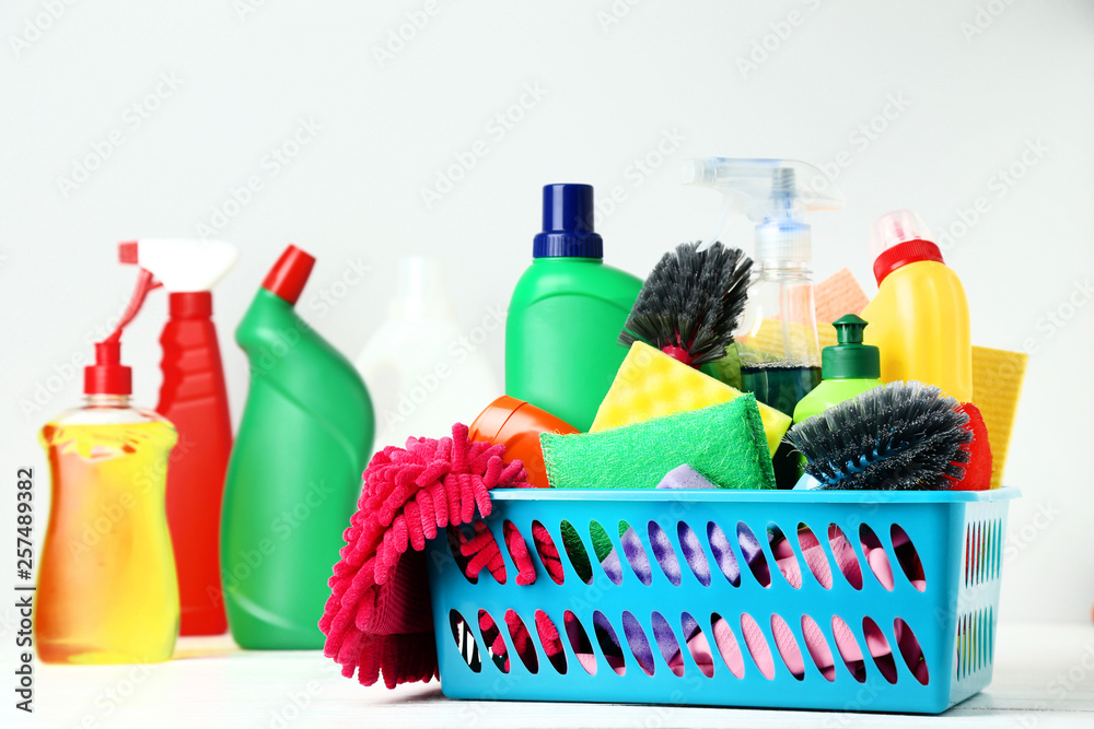 Bottles with detergent and cleaning tools on grey background
