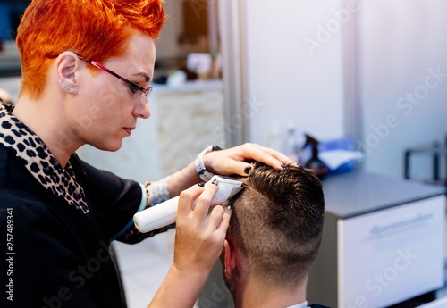 Hairdresser cutting customer hair with electric trimmer