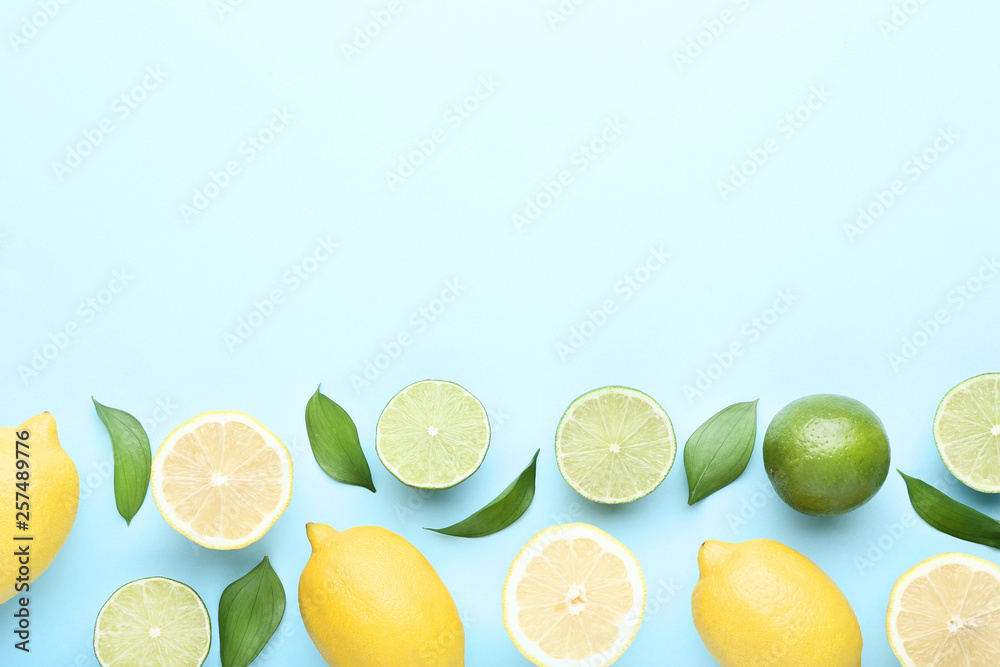 Ripe lemons and limes with green leafs on blue background