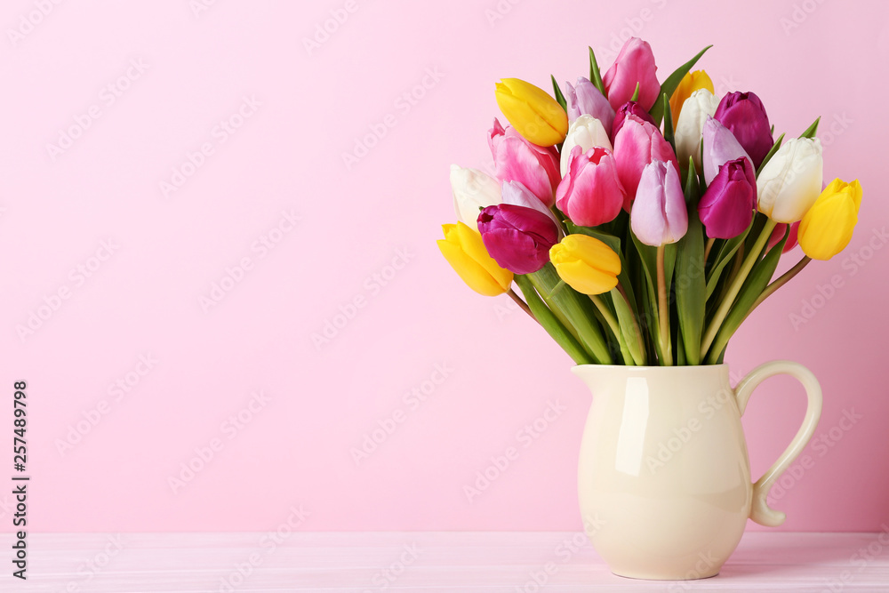 Fototapeta premium Bouquet of tulips in jug on wooden table