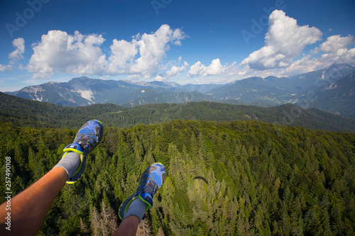 Feet of paraglider flying above forest, near Begunje and Radovljica, Upper Carniola, Slovenia